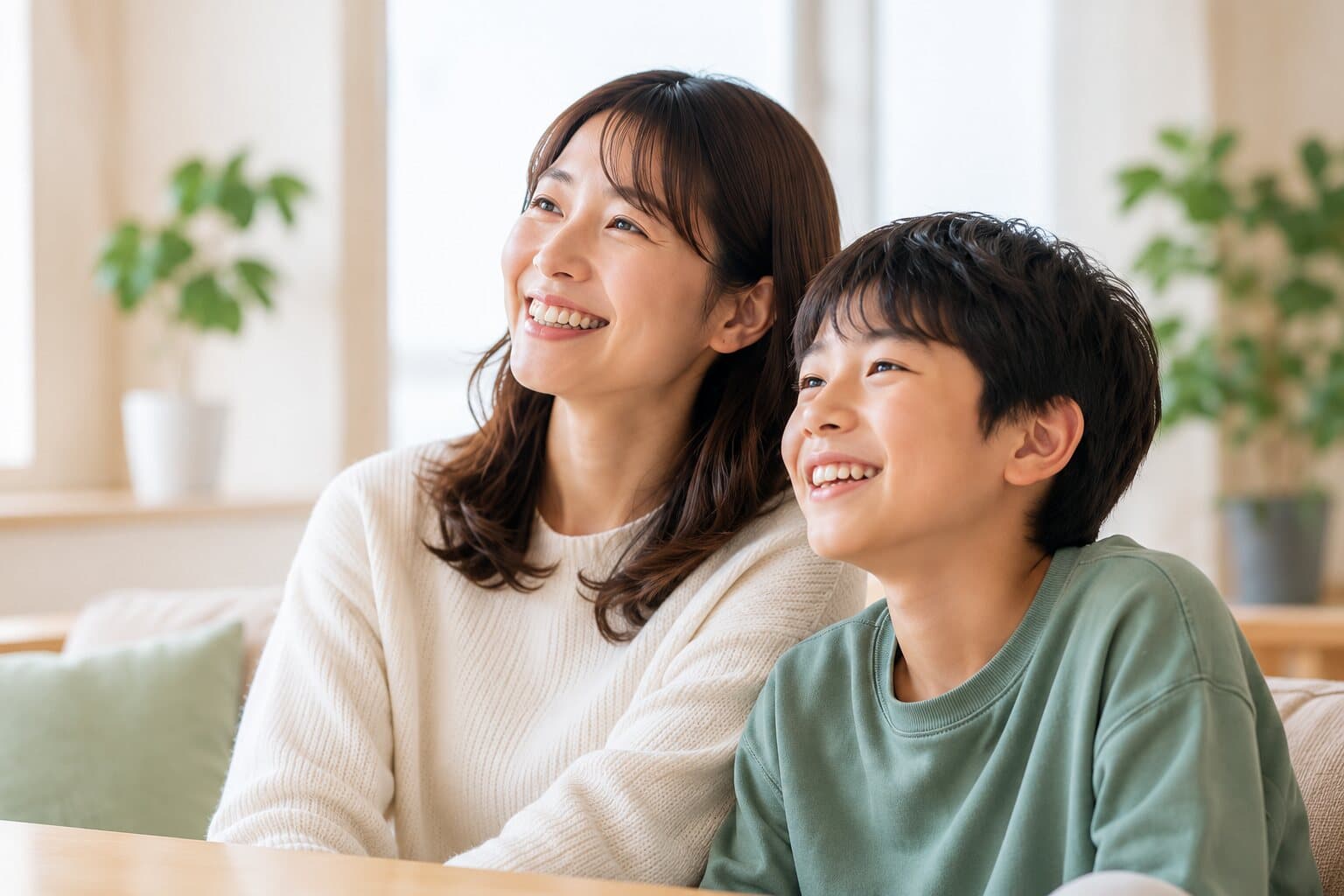 明るいリビングで、同じ方向を見て笑う母親と息子